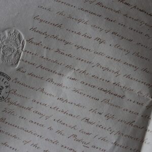 Mano escribiendo con bolígrafo sobre un documento en papel