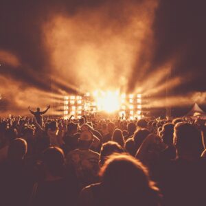 Público a contraluz frente a un escenario iluminado durante un concierto nocturno