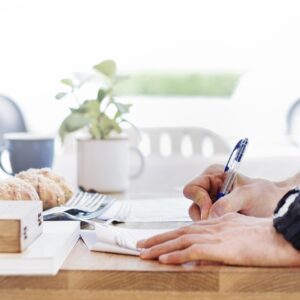 Persona firmando un documento con bolígrafo sobre una mesa