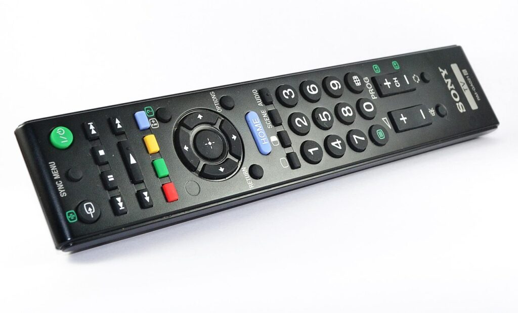 Mano sosteniendo un control remoto apuntando a un televisor