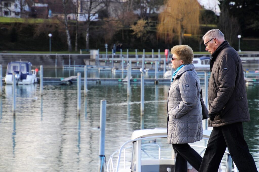 Pareja de adultos mayores caminando junto a un lago