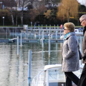 Pareja de adultos mayores caminando junto a un lago
