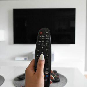 Televisor encendido en una sala de estar junto a un control remoto