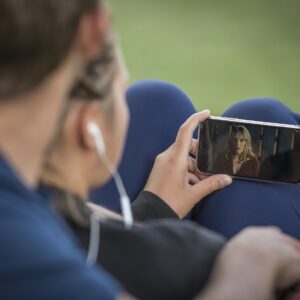 Persona viendo un video en su teléfono móvil al aire libre
