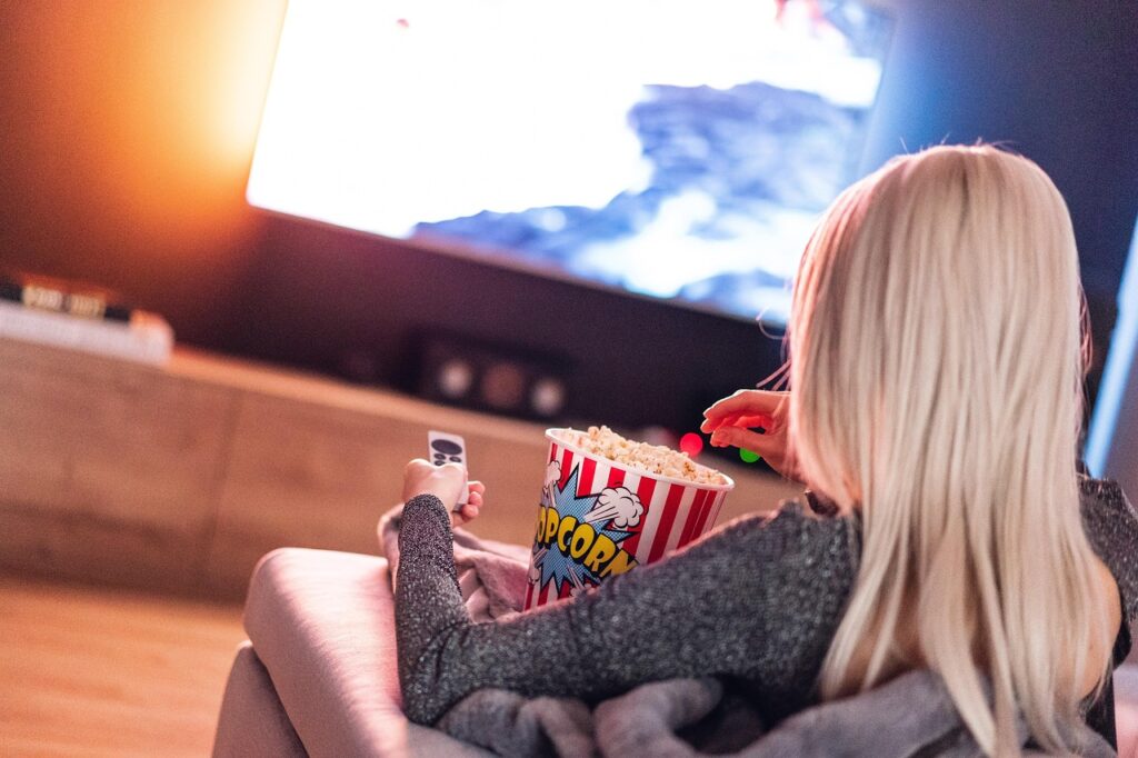 Persona comiendo palomitas mientras ve una película en el televisor