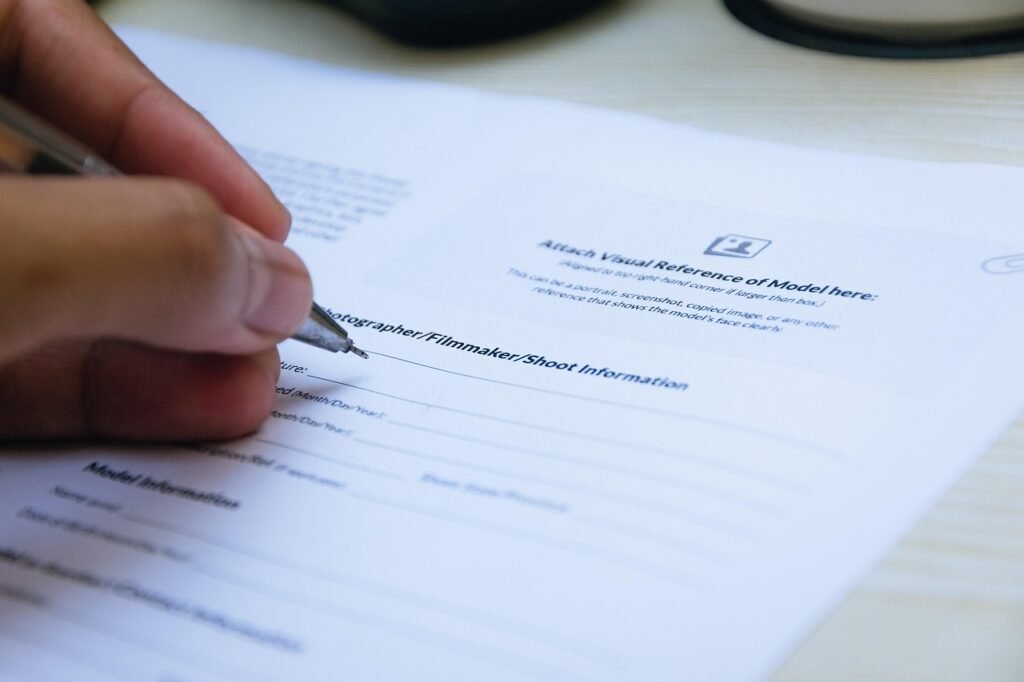 Mano firmando un documento en papel con bolígrafo