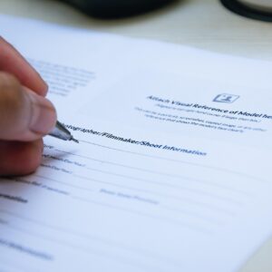 Mano firmando un documento en papel con bolígrafo